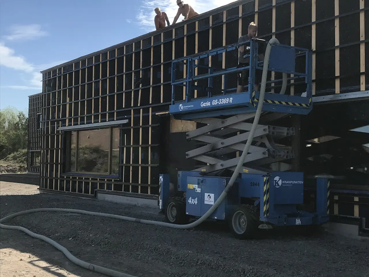 Skolbyggnad med saxlift och isoleringsslang vid fasaden
